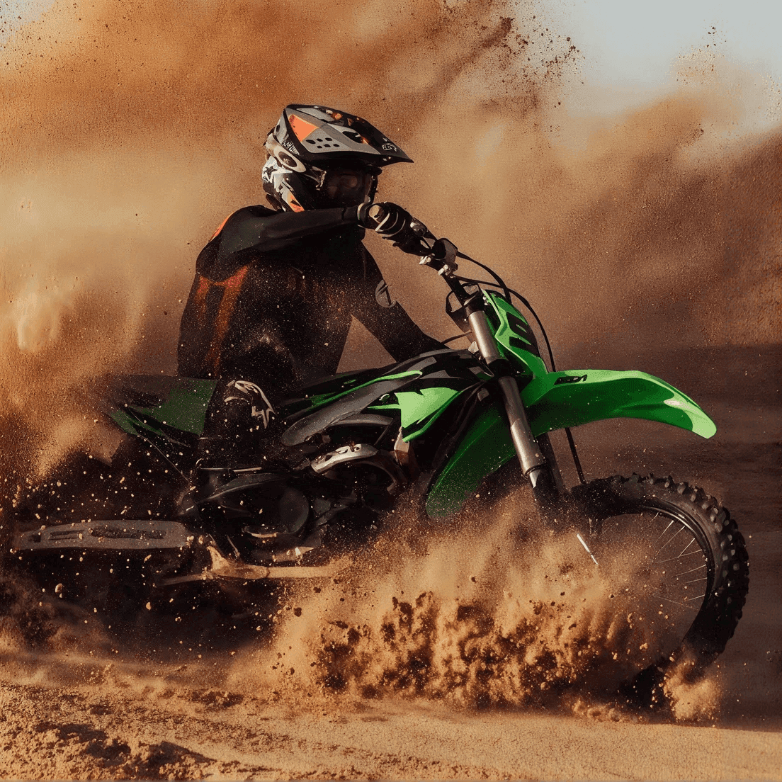 Pilota di motocross che solleva sabbia e polvere con una moto da fuoristrada verde in una curva stretta.